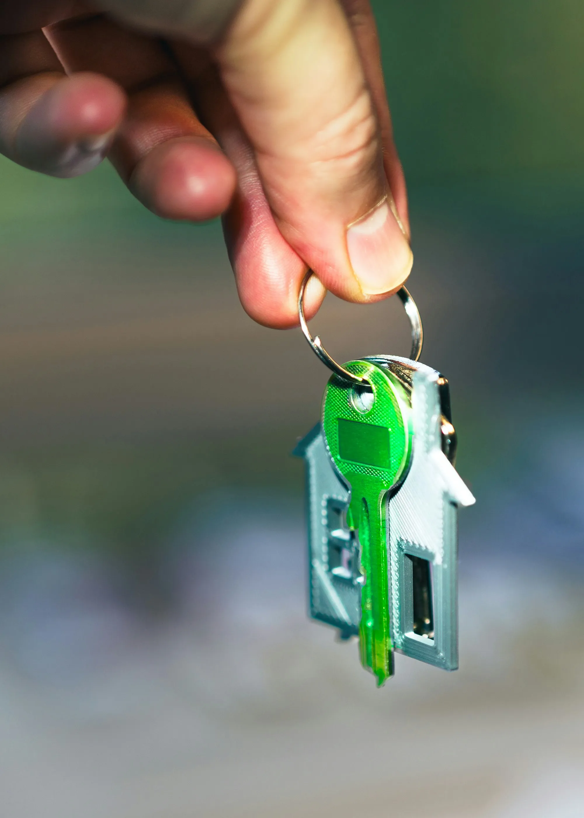 Hand holding keys on a green house keychain