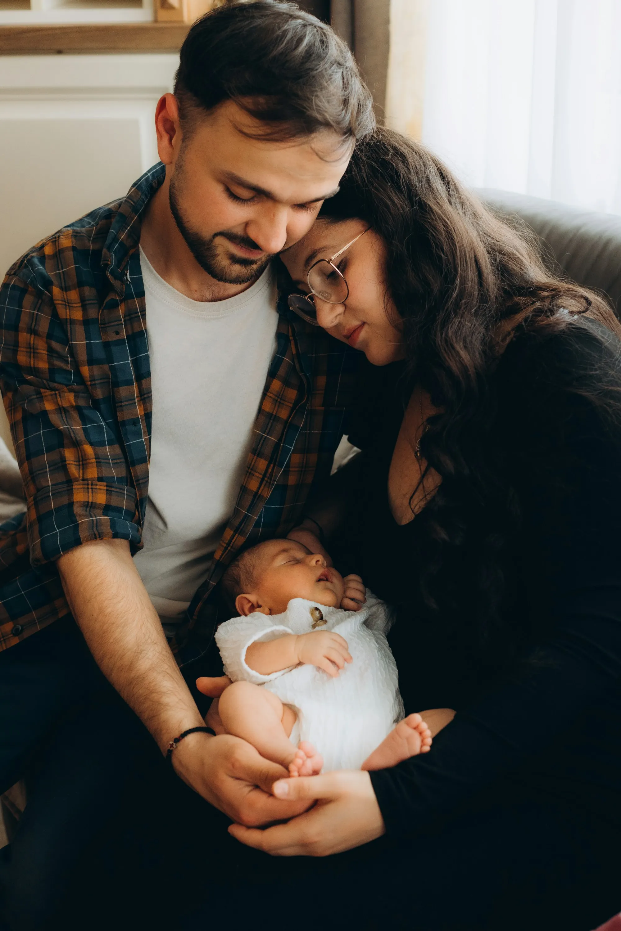 Parents cradling a newborn wrapped in a blanket
