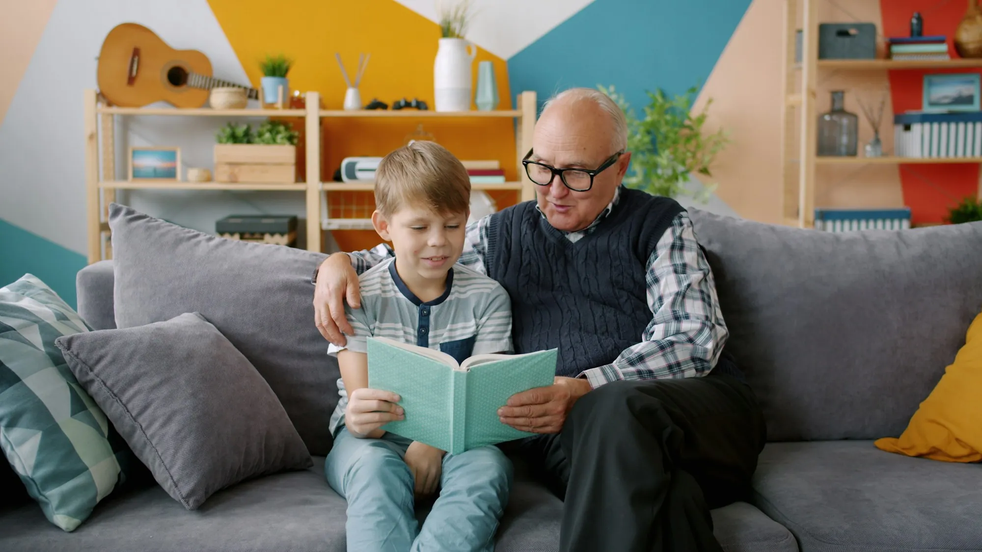 Grandfather reading a book with his grandson on the couch